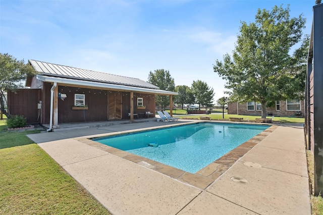 view of swimming pool featuring an outdoor structure, a patio, and a lawn