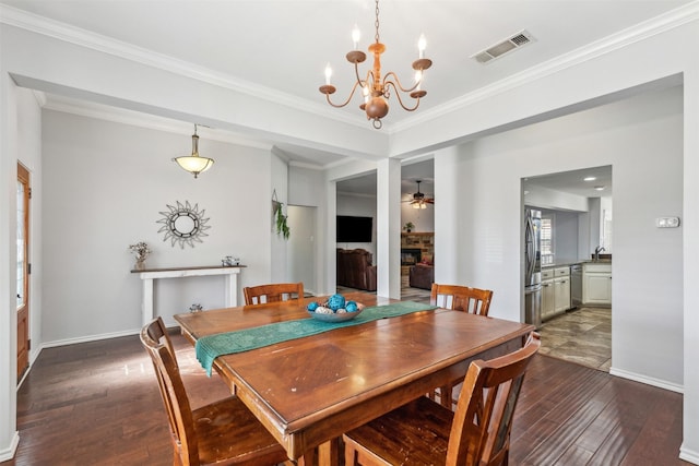 dining space featuring sink, crown molding, dark hardwood / wood-style flooring, a fireplace, and ceiling fan with notable chandelier