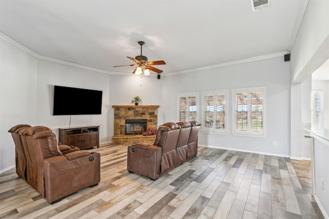 living room featuring crown molding, a stone fireplace, ceiling fan, and light wood-type flooring