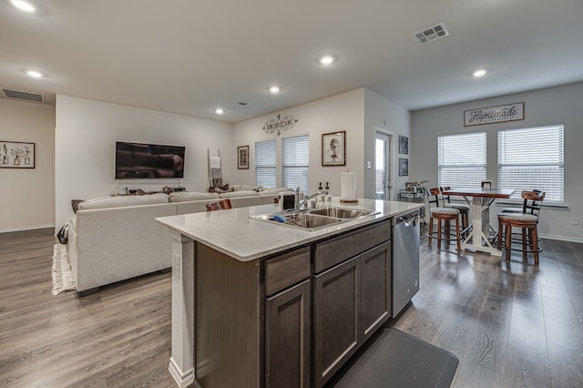 kitchen featuring sink, hardwood / wood-style floors, dark brown cabinets, an island with sink, and stainless steel dishwasher