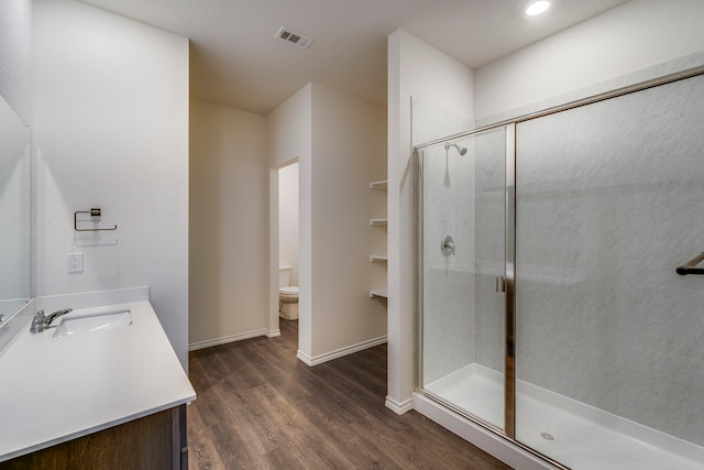 bathroom featuring vanity, a shower with shower door, hardwood / wood-style floors, and toilet