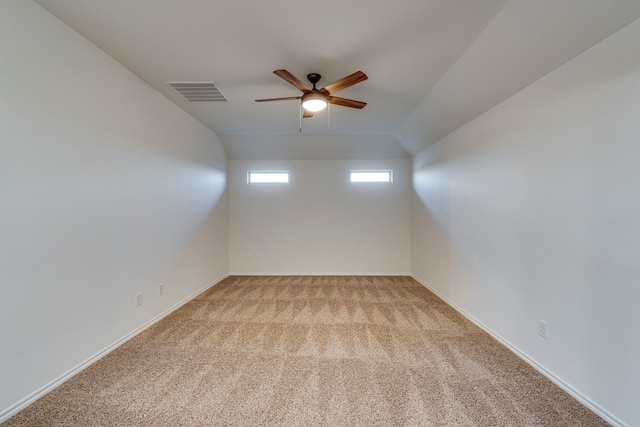 spare room with ceiling fan, light colored carpet, and vaulted ceiling