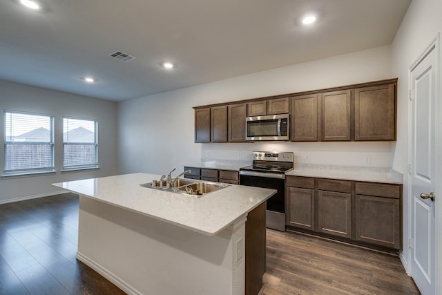 kitchen with sink, dark wood-type flooring, stainless steel appliances, and an island with sink