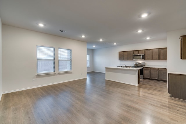 kitchen featuring stainless steel appliances, sink, a center island with sink, and light hardwood / wood-style floors