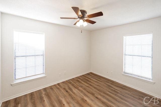 empty room featuring ceiling fan, plenty of natural light, and dark hardwood / wood-style flooring