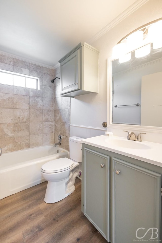 full bathroom with tiled shower / bath, wood-type flooring, vanity, toilet, and crown molding