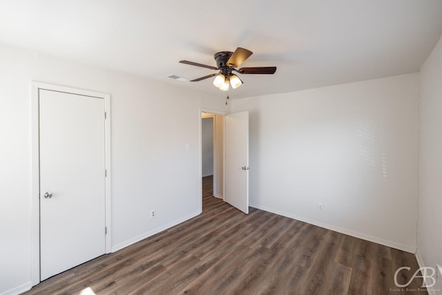 unfurnished bedroom featuring dark hardwood / wood-style flooring, ceiling fan, and a closet