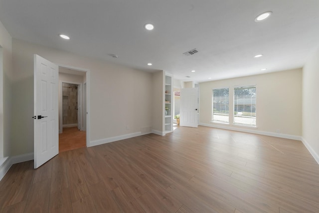 spare room featuring built in shelves and light wood-type flooring