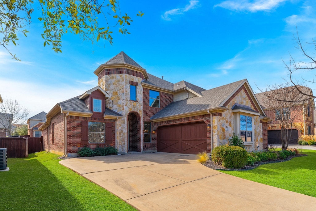 view of front of house featuring cooling unit, a garage, and a front lawn