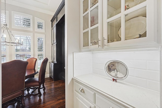 dining room with ornamental molding, dark hardwood / wood-style flooring, and an inviting chandelier