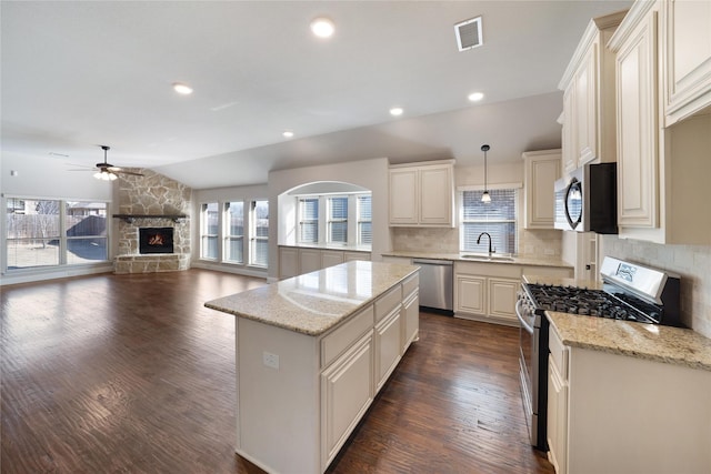 kitchen with a kitchen island, a fireplace, decorative light fixtures, tasteful backsplash, and stainless steel appliances