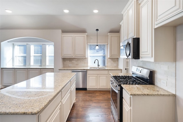 kitchen featuring hanging light fixtures, decorative backsplash, stainless steel appliances, and light stone countertops