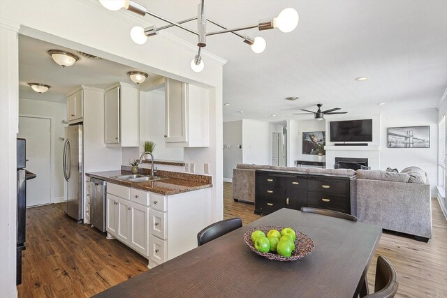 kitchen featuring sink, appliances with stainless steel finishes, white cabinetry, dark hardwood / wood-style flooring, and dark stone counters