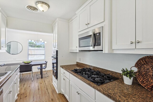 kitchen with sink, appliances with stainless steel finishes, light hardwood / wood-style floors, white cabinets, and dark stone counters