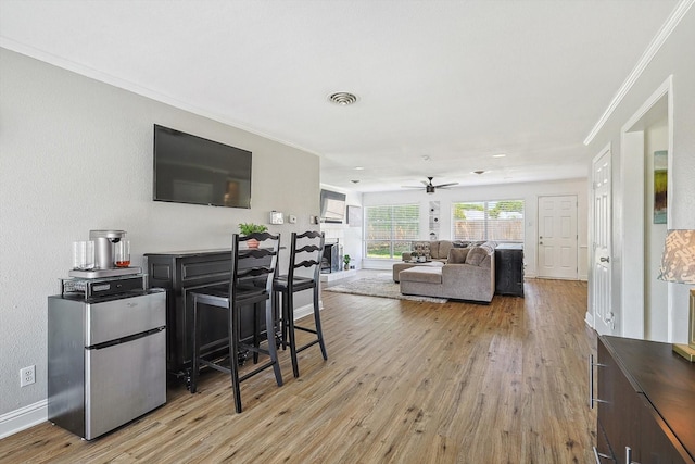 living room with ceiling fan, ornamental molding, and light hardwood / wood-style flooring