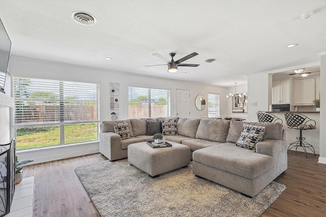 living room featuring ornamental molding, a healthy amount of sunlight, ceiling fan with notable chandelier, and wood-type flooring