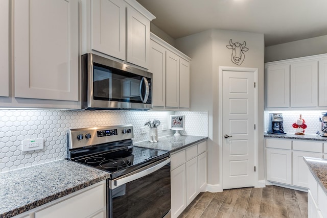 kitchen featuring stainless steel appliances, white cabinets, light stone counters, and light hardwood / wood-style flooring