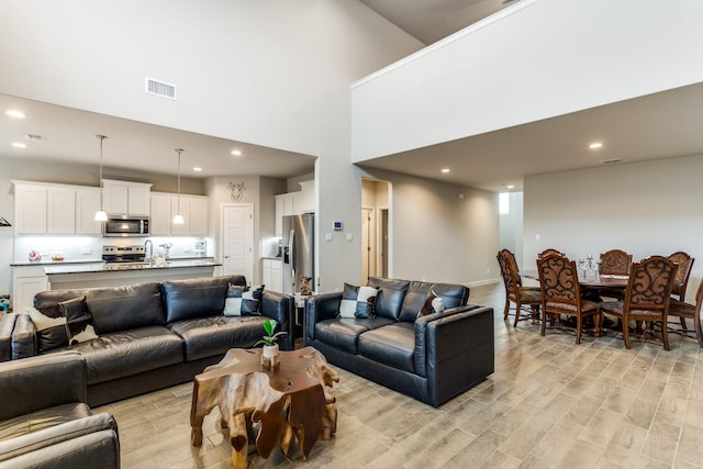 living room with light hardwood / wood-style flooring and a high ceiling