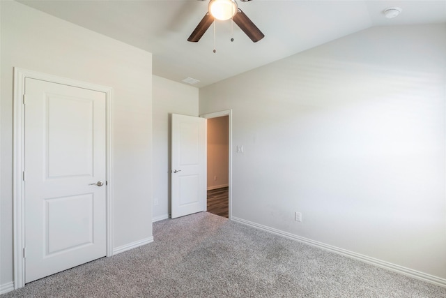 unfurnished bedroom with a ceiling fan, carpet, vaulted ceiling, and baseboards