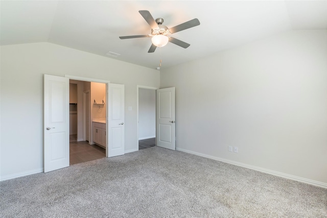 unfurnished bedroom with ceiling fan, lofted ceiling, light colored carpet, and ensuite bath