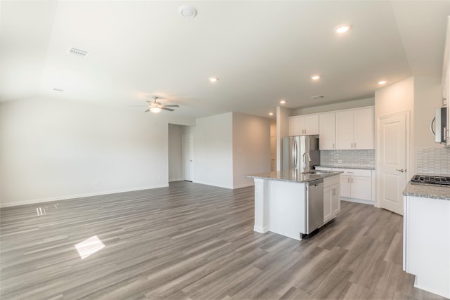 kitchen with stainless steel appliances, visible vents, decorative backsplash, light wood finished floors, and an island with sink