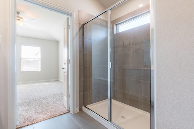 bathroom featuring ceiling fan, a shower with door, tile patterned floors, and a healthy amount of sunlight