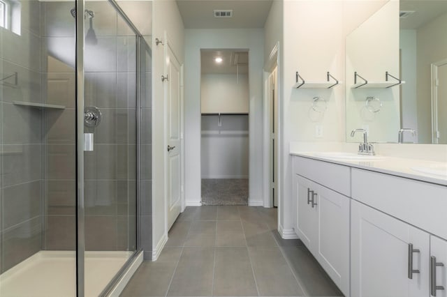 full bathroom featuring double vanity, tile patterned floors, a sink, and a shower stall