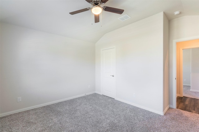 carpeted spare room with lofted ceiling, ceiling fan, visible vents, and baseboards