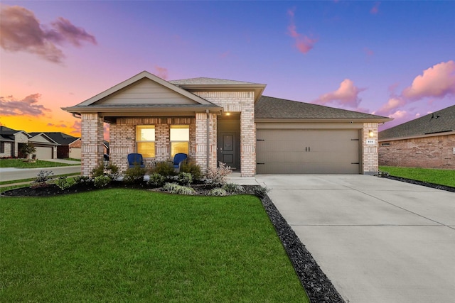 view of front of house with an attached garage, covered porch, brick siding, driveway, and a lawn