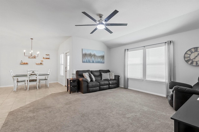 carpeted living room featuring lofted ceiling, ceiling fan with notable chandelier, tile patterned flooring, and baseboards