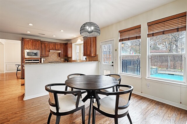 kitchen with tasteful backsplash, stainless steel refrigerator with ice dispenser, and light stone countertops