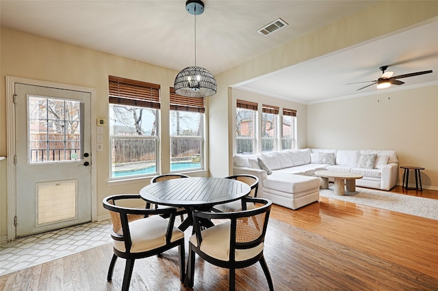 dining area with crown molding, ceiling fan with notable chandelier, and light hardwood / wood-style flooring