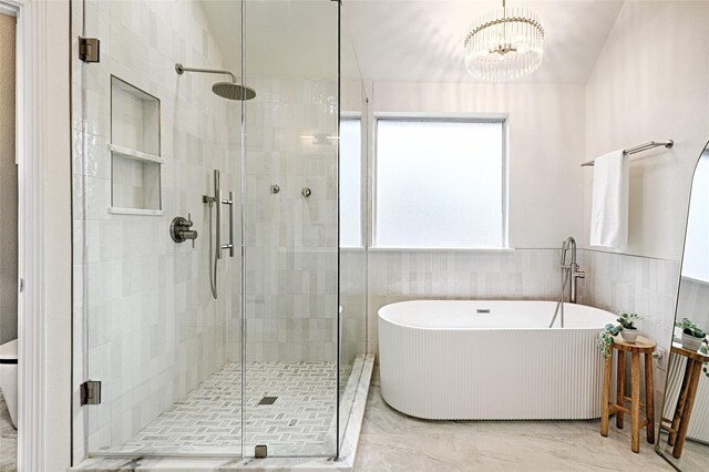 bathroom featuring an inviting chandelier, independent shower and bath, and tile walls