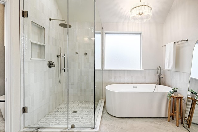 bathroom featuring tile walls, shower with separate bathtub, and an inviting chandelier