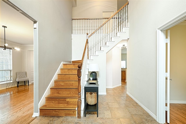 staircase with wood-type flooring and a towering ceiling