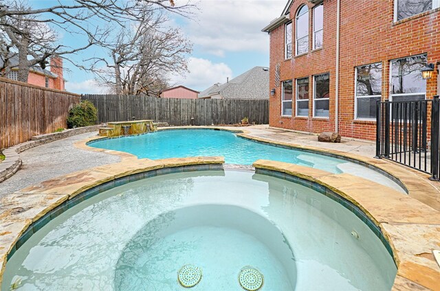 view of swimming pool featuring pool water feature and an in ground hot tub