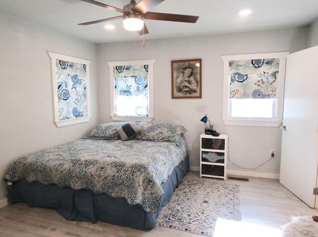 bedroom with ceiling fan, multiple windows, and light wood-type flooring