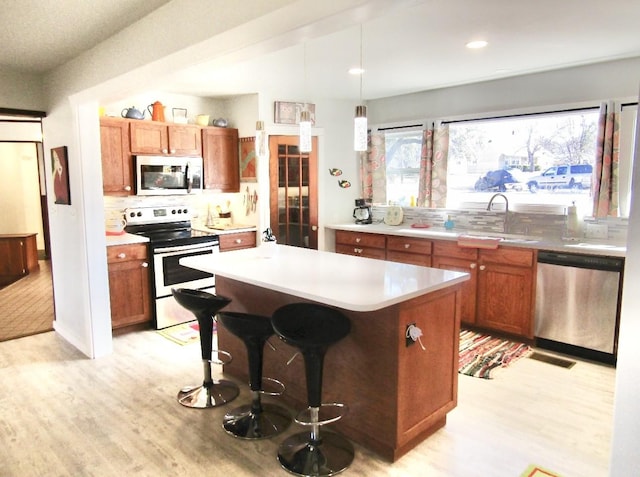 kitchen featuring a kitchen island, a breakfast bar, sink, hanging light fixtures, and stainless steel appliances