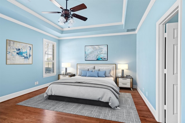 bedroom with a raised ceiling, ornamental molding, ceiling fan, and dark hardwood / wood-style flooring