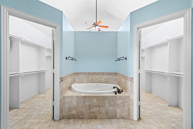 bathroom with a relaxing tiled tub, ceiling fan, tile patterned flooring, and vaulted ceiling