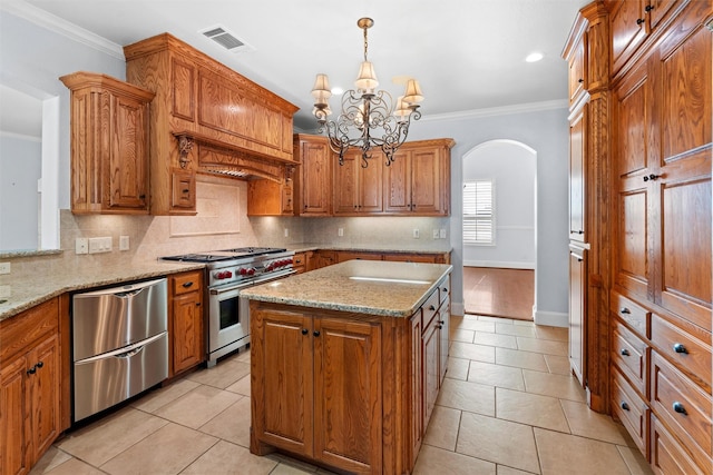 kitchen featuring appliances with stainless steel finishes, a center island, light stone counters, ornamental molding, and decorative light fixtures