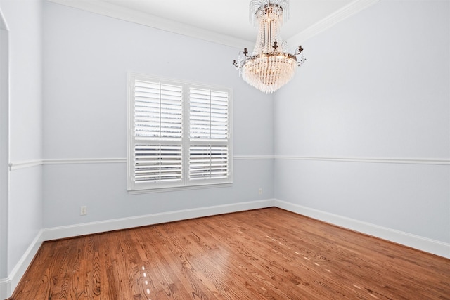 spare room featuring hardwood / wood-style flooring, crown molding, and a notable chandelier