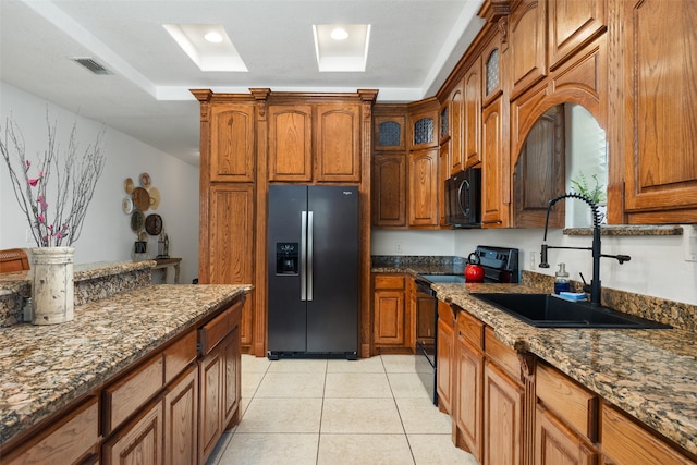 kitchen featuring light tile patterned flooring, dark stone countertops, sink, and black appliances