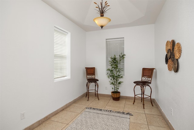 living area with light tile patterned floors and a raised ceiling