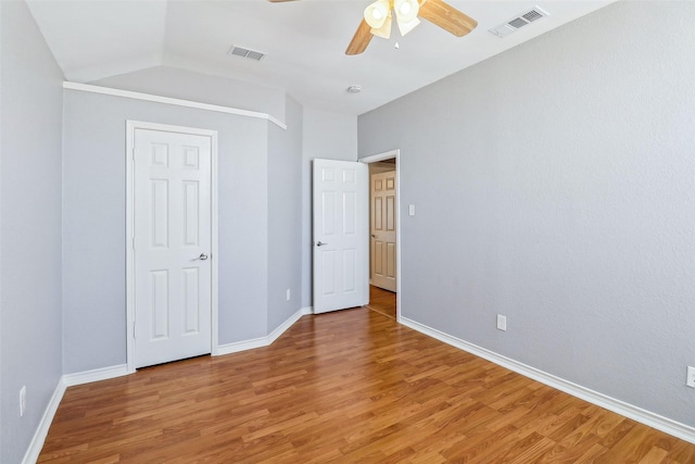 unfurnished bedroom with lofted ceiling, hardwood / wood-style flooring, and ceiling fan