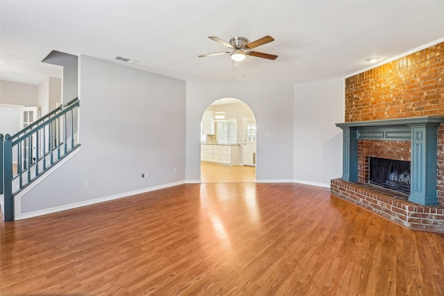 unfurnished living room featuring hardwood / wood-style flooring, ceiling fan, and a fireplace