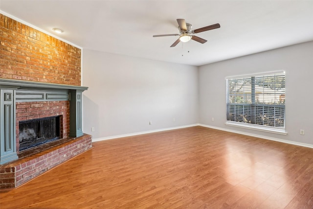 unfurnished living room with a brick fireplace, wood-type flooring, and ceiling fan