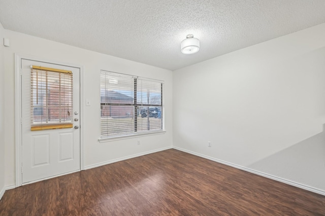 empty room with plenty of natural light, dark hardwood / wood-style floors, and a textured ceiling