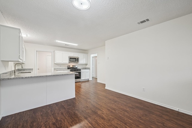 kitchen featuring appliances with stainless steel finishes, sink, white cabinets, light stone countertops, and a textured ceiling