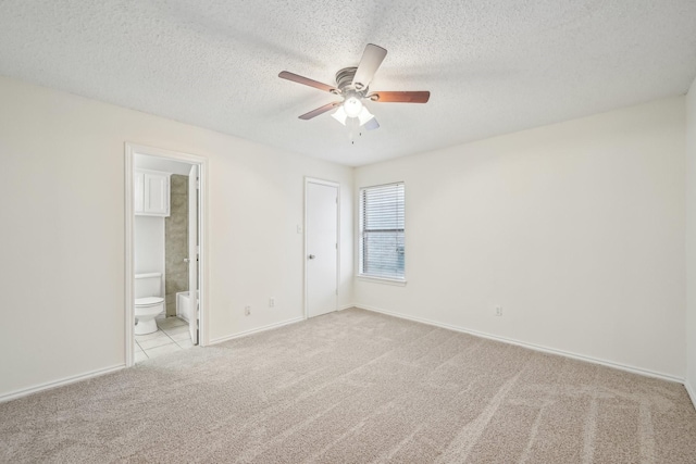 unfurnished bedroom featuring ceiling fan, connected bathroom, a textured ceiling, light carpet, and a closet